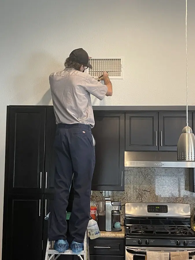 Technician inspecting an air vent during HVAC service in Albert Lea